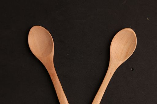 An overhead shot of wooden spoons on a black background