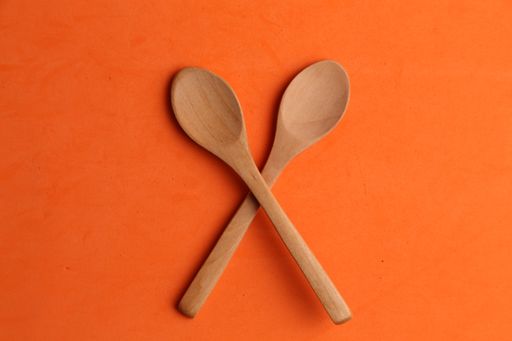 A closeup shot of wooden cooking spoons on an orange background