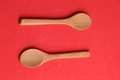 A high angle shot of two wooden spoons isolated on red surface