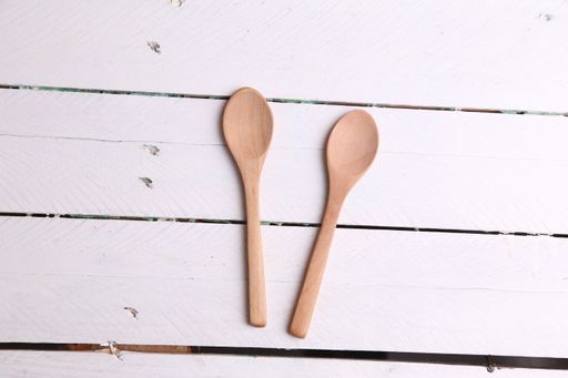A top view of two wooden kitchen spoons on a white table