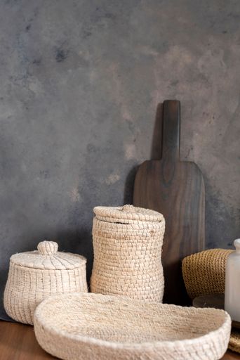 A vertical closeup of kitchen utensils against a gray textured wall.