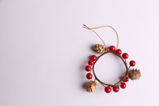 An overhead shot of a wooden Christmas ornament with small pine cones isolated on a white background