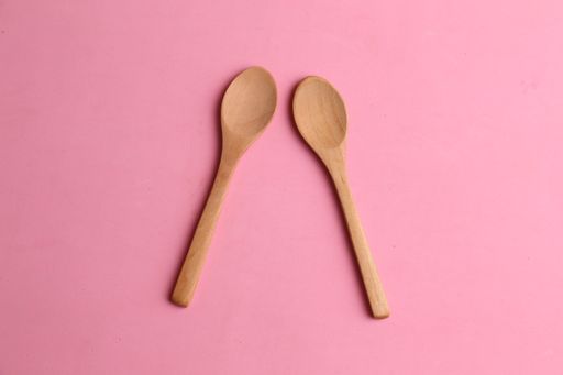 An overhead shot of wooden spoons isolated on a pink background