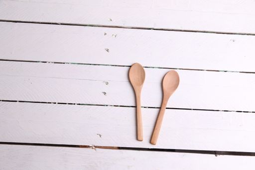 A closeup shot of a wooden cooking spoon on a wooden background