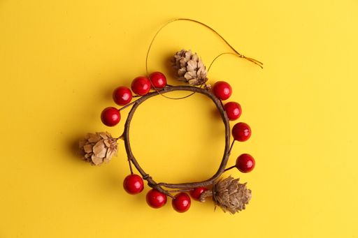 A top view of a decorative trinket with pinecones and red circles on a yellow surface