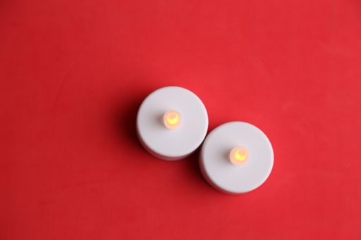 A top view of white plastic led candles on a red background