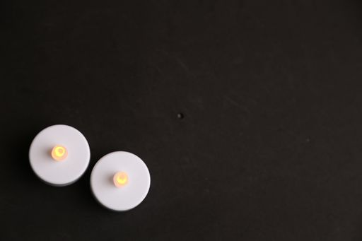 An overhead shot of white plastic led candles on a black surface