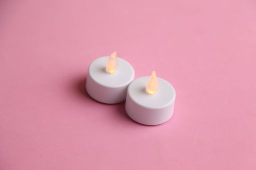 A high angle shot of two fake plastic candles isolated on a pink surface