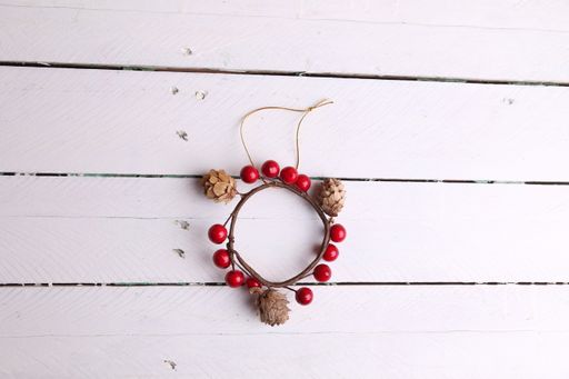 A top view of a decorative wreath with balls and cones on a white wooden surface