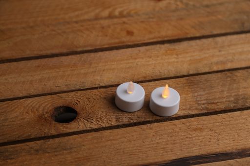 A high angle shot of two small electric candles on a wooden surface
