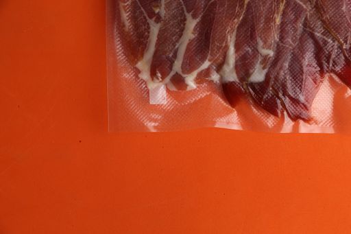 A high angle shot of raw meat in a plastic bag isolated on an orange surface