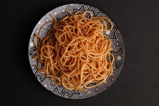 A high angle shot of a plate of delicious spaghetti isolated on a black surface