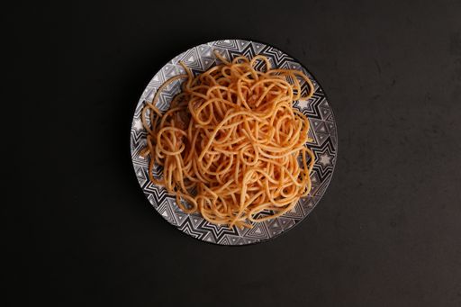 A top view of a plate of delicious spaghetti pasta on a black surface