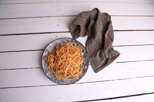 A high angle shot of a plate of spaghetti on a wooden surface