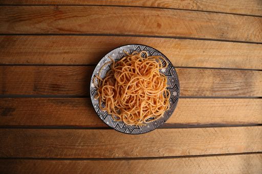 A top view of a plate with tomato spaghetti on a wooden table