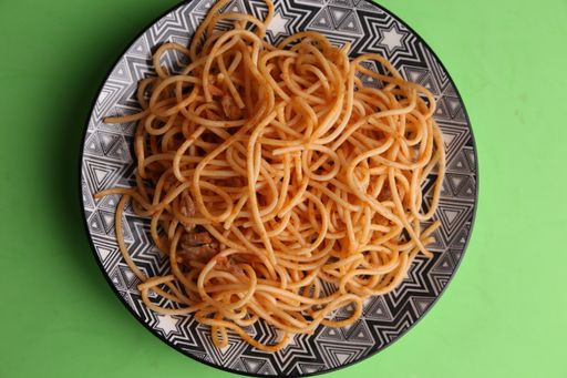 An overhead shot of pasta with sauce in a plate isolated on a green background