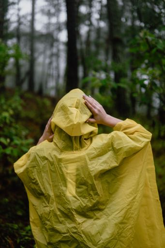 A person in yellow raincoat walking in a wet forest