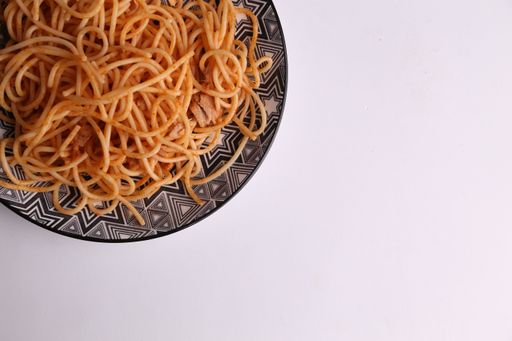 A top view of a plate of delicious spaghetti with tomato sauce isolated on a white surface