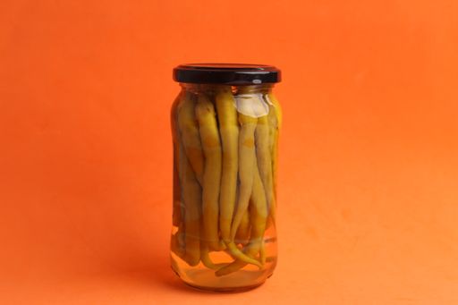 A closeup shot of chili peppers in glass canned jar with vinegar
