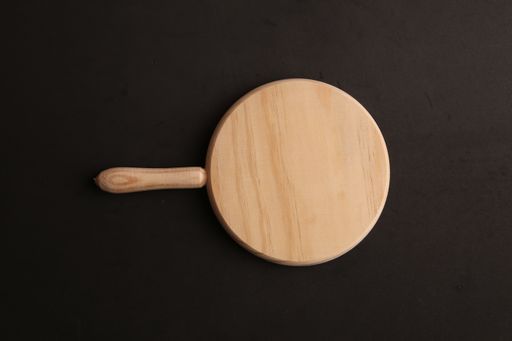 A top view of a wooden cutting board on a brown surface under the lights