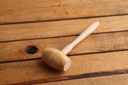 A closeup shot of a small wooden mallet isolated on a wooden surface