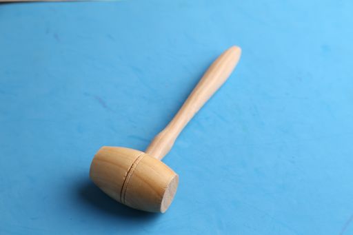 A high angle shot of a wooden hammer isolated on a blue surface
