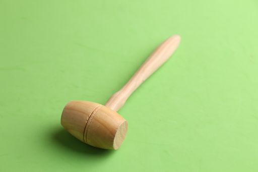 A high angle shot of a wooden hammer isolated on a green surface