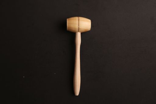 A wooden meat mallet on a black background