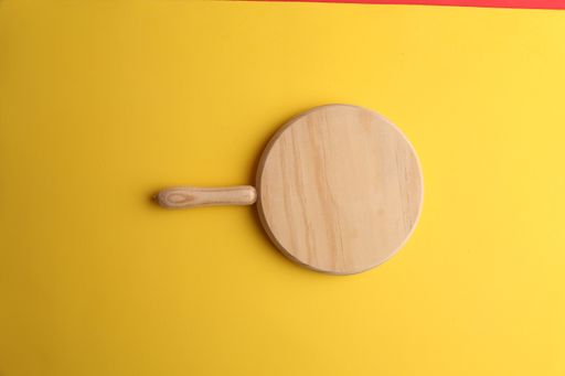 A high angle shot of a wooden plate isolated on a yellow surface