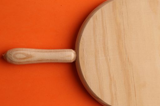 An overhead shot of wooden cutting board with an orange background