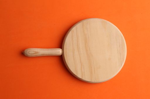 A round cheese board on an orange background