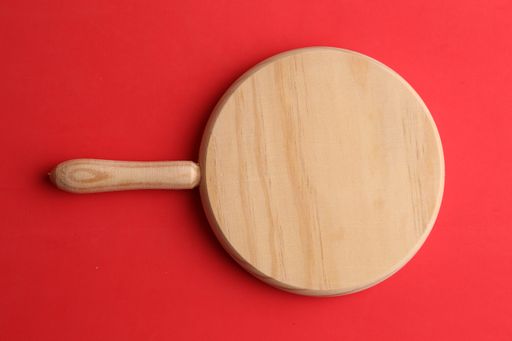 An overhead shot of a round wooden board isolated on a red background