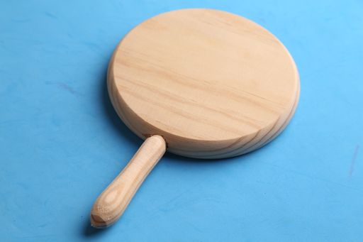 A closeup of the round wooden serving board on a blue surface
