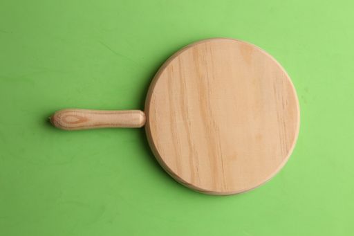 A closeup shot of a wooden chopping board  isolated on a green background