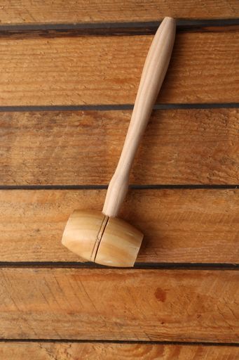 A vertical high angle shot of a wooden hammer isolated on a wooden surface