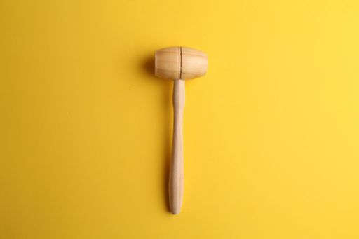 A top view of a wooden kitchen hammer isolated on a yellow background