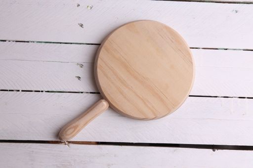 A top view of a round kitchen board on a white wooden background