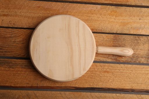 An overhead shot of a small round wooden cutting board on a table