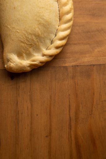 A vertical shot of a pizza calzone on a wooden surface