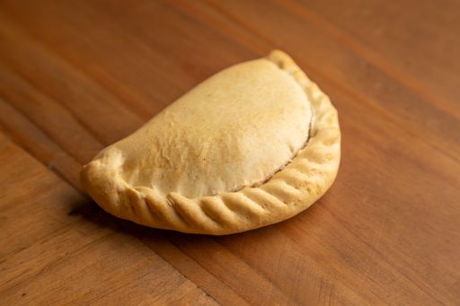 A closeup shot of a delicious empanada on a wooden surface
