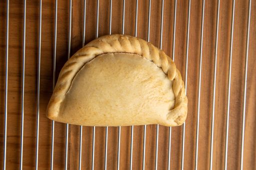 A top view closeup of a delicious empanada on a brown table