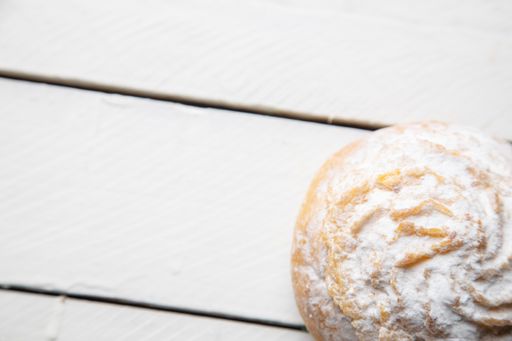 A top view of a delicious coconut cake with sugar powder on a white wooden surface