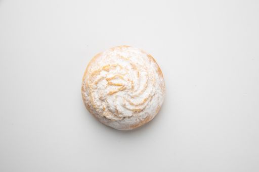 A high angle shot of a delicious cookie covered with sugar powder on a white surface