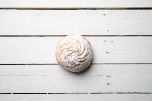 A closeup shot of a delicious cookie with sugar powder on a wooden surface