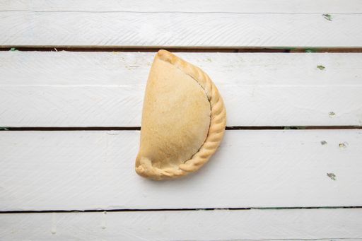 An overhead shot of an Empanada on a wooden table under the lights