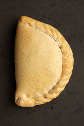 A vertical shot of a delicious empanada isolated on a black surface