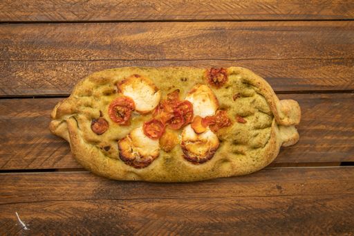 A toast with tomato, pesto and goat cheese on wooden background
