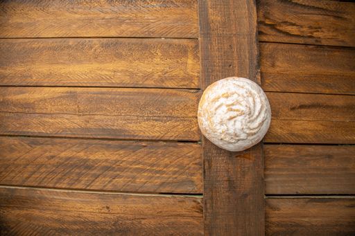 A top view of a coconut cookie with sugar powder on a wooden table
