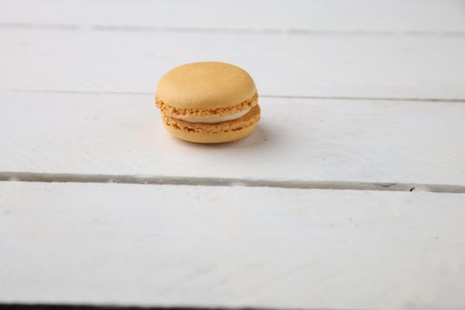 A closeup shot of yellow macaron on white background