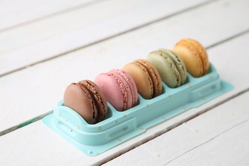 A high angle shot of some delicious and colorful macarons isolated on a white wooden surface